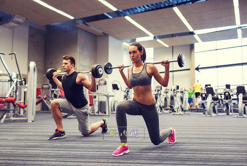 young man and woman training with barbell in gym